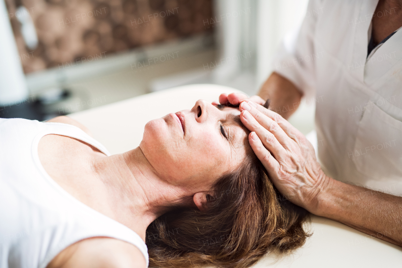 An unrecognizable physiotherapist working with an old female patient.