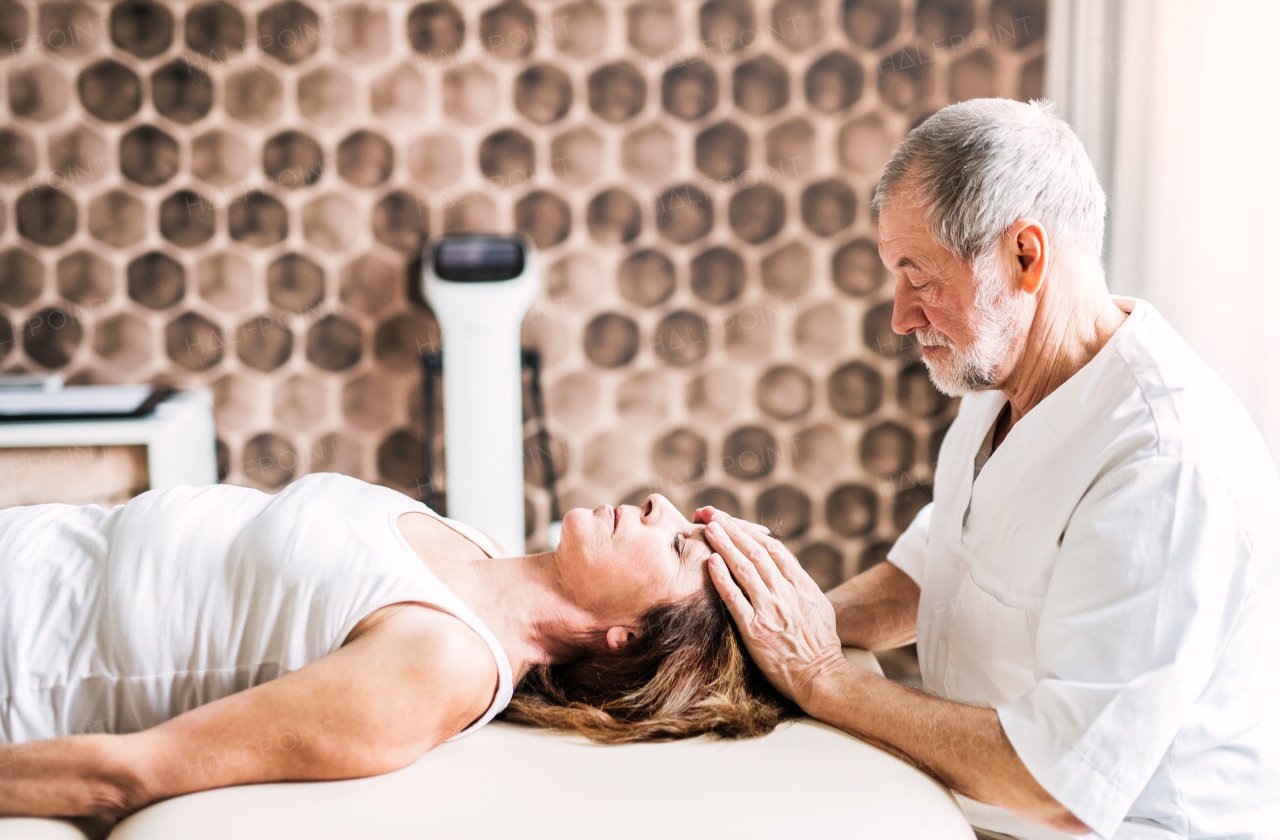 Senior physiotherapist working with an old female patient.