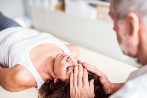 Unrecognizable senior physiotherapist working with an old female patient.