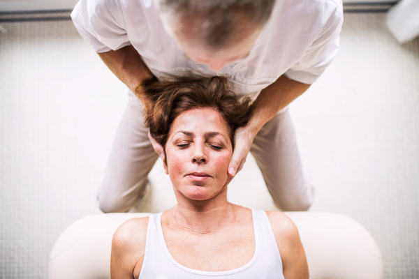 Unrecognizable senior physiotherapist working with an old female patient. Top view.