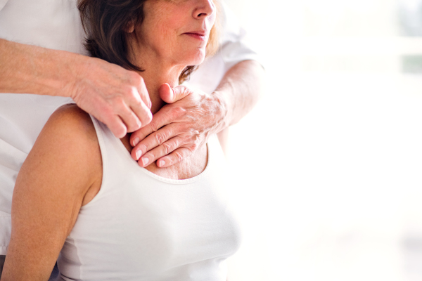 An unrecognizable physiotherapist working with an old female patient. Copy space.