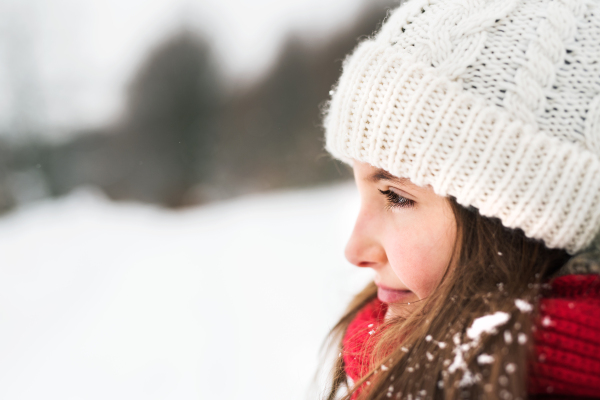 Portrait of a small girl in winter nature. Side view. Close up.