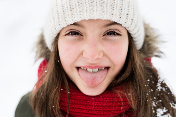 A small girl having fun in snow. Winter nature. Close up.