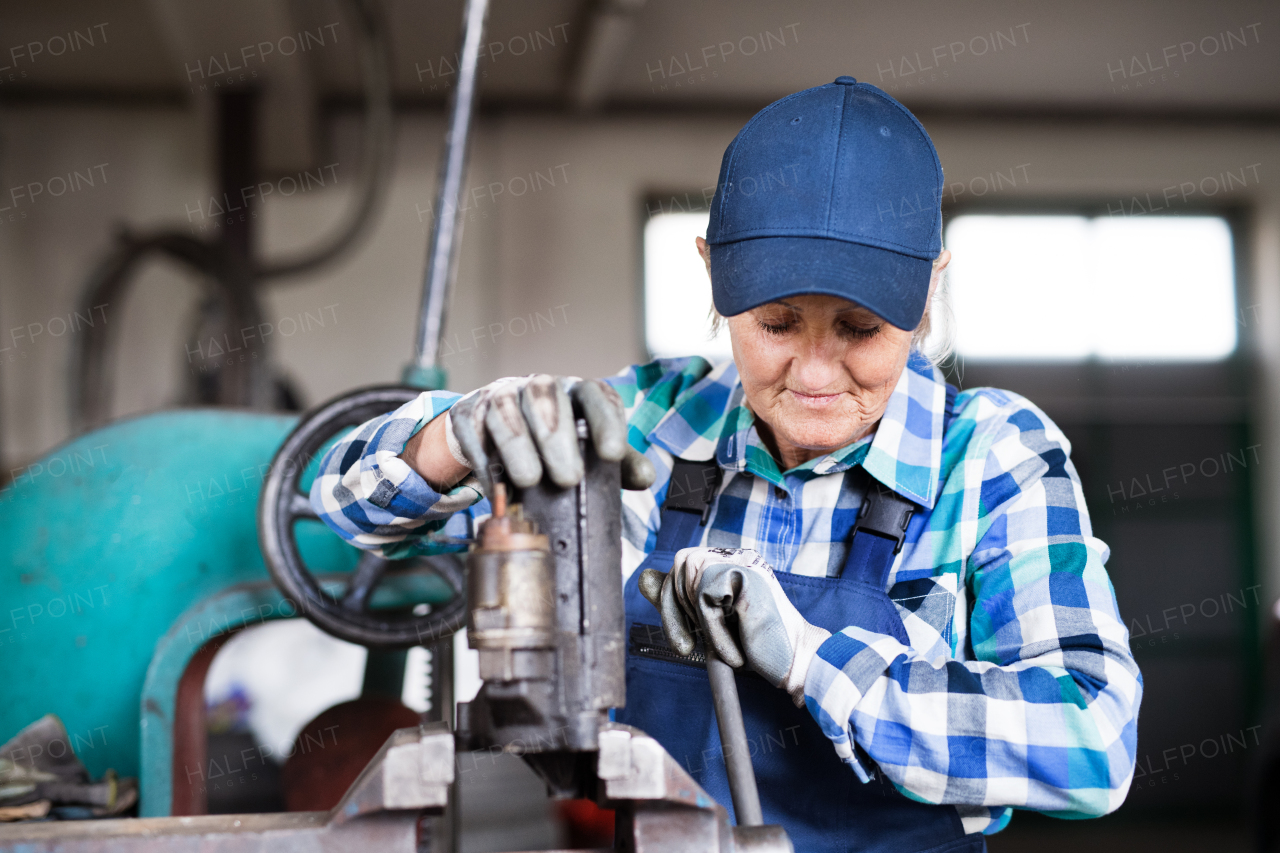 Female mechanic repairing a car. A senior woman working in a garage.