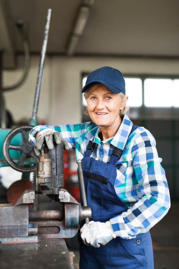 Female mechanic repairing a car. A senior woman working in a garage.