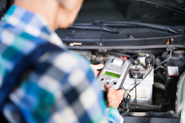 Unrecognizable female mechanic repairing a car. A senior woman working in a garage.