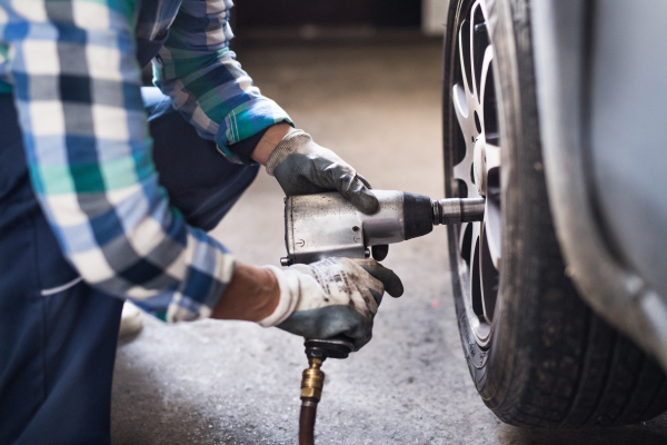 Female mechanic repairing a car. An unrecognizable woman working in a garage.