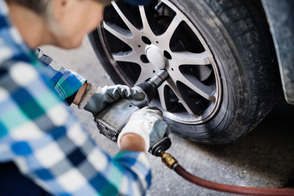 Female mechanic repairing a car. An unrecognizable woman working in a garage.