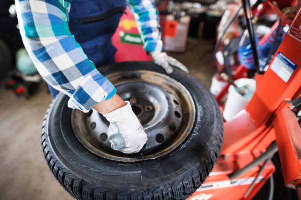 Female mechanic repairing a car. An unrecognizable woman working in a garage.