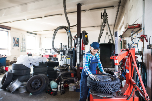 Female mechanic repairing a car. A senior woman working in a garage.