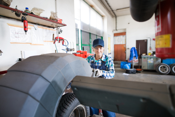 Female mechanic repairing a car. A senior woman working in a garage.