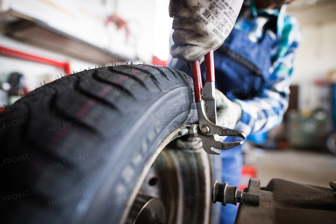 Female mechanic repairing a car. An unrecognizable woman working in a garage.