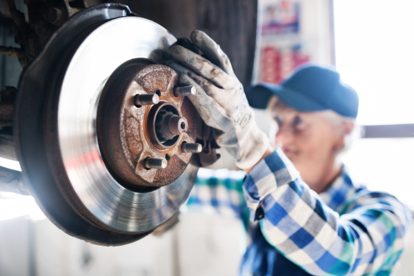 Female mechanic repairing a car. A senior woman working in a garage.