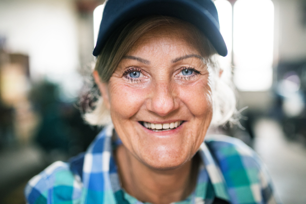 Female mechanic repairing a car. A senior woman standing in a garage. Close up.