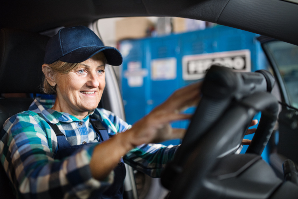 Female mechanic repairing a car. A senior woman working in a garage.