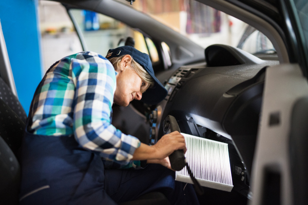 Female mechanic repairing a car. A senior woman working in a garage.