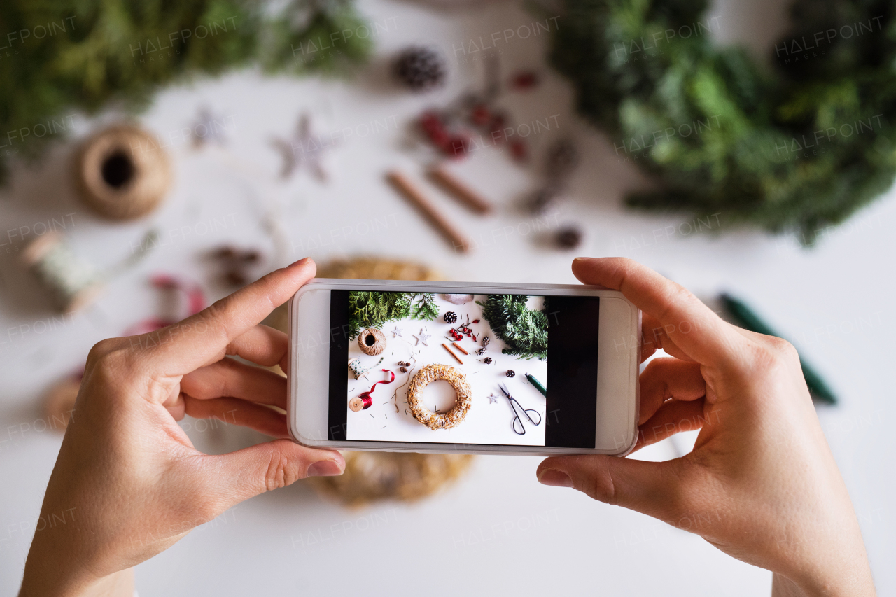 Christmas composition on a white background. Flat lay. Female hands holding a smartphone, taking a photograph.