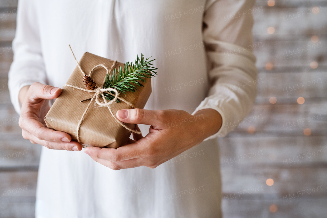 Unrecognizable young woman holding wrapped Christmas present.