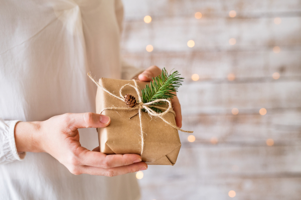 Unrecognizable young woman holding wrapped Christmas present.