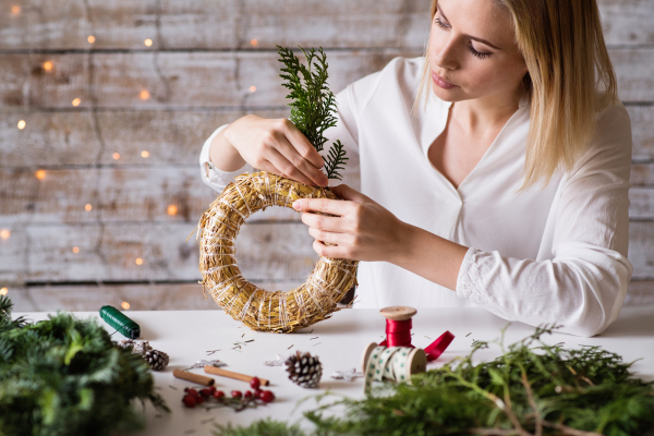 Beautiful young woman making a Christmas wreath.