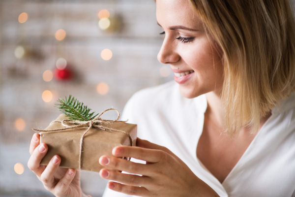 Beautiful young woman holding wrapped Christmas present.