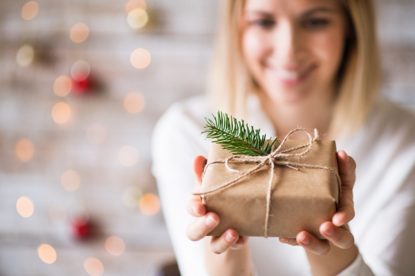 Beautiful young woman holding wrapped Christmas present.