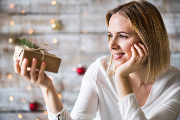 Beautiful young woman holding wrapped Christmas present.