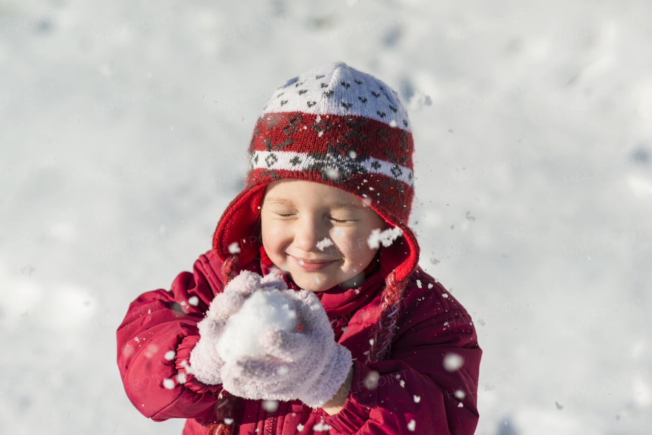 Little girl is playing outside in cold winter.