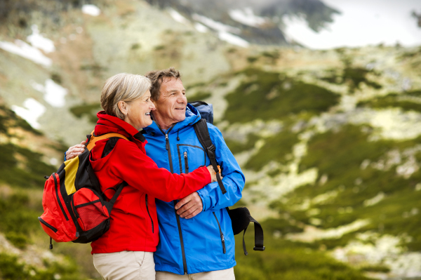 Beautiful senior couple of tourists in the mountains together, spring time.