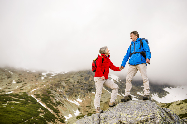 Beautiful senior couple of tourists in the mountains together, spring time.