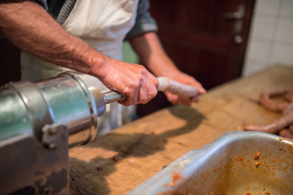 Unrecognizable man making sausages the traditional way using sausage filler. Homemade sausage.