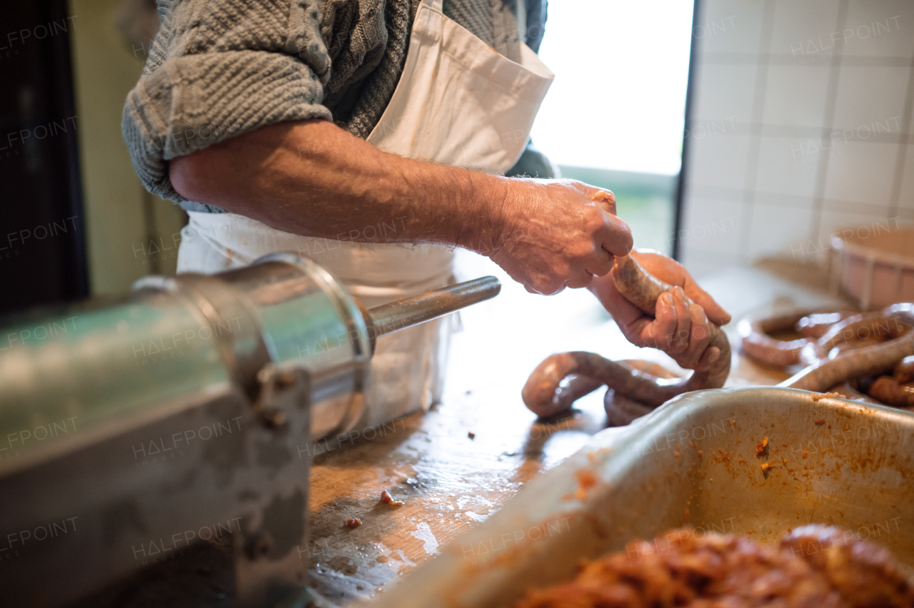 Unrecognizable man making sausages the traditional way using sausage filler. Homemade sausage.