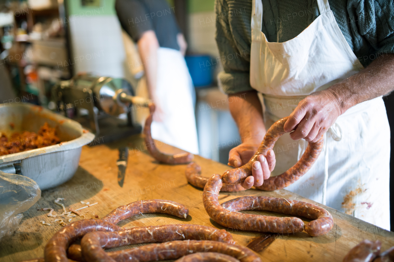 Two unrecognizable men making sausages the traditional way using sausage filler. Homemade sausage.