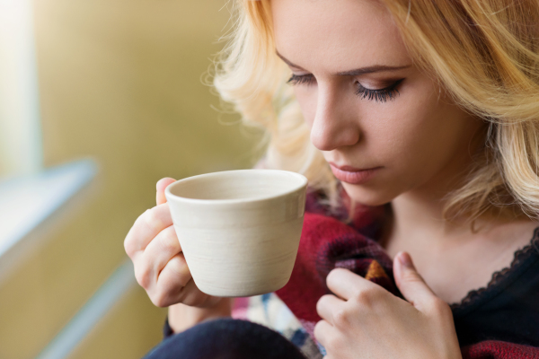 Beautiful woman relaxing at home with cup of coffee