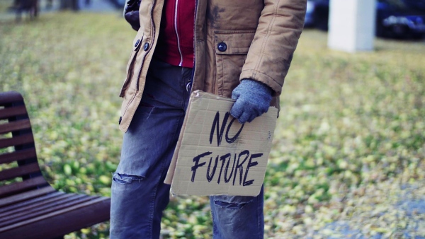 A midsection of portrait of homeless beggar man walking outdoors in park in autumn.