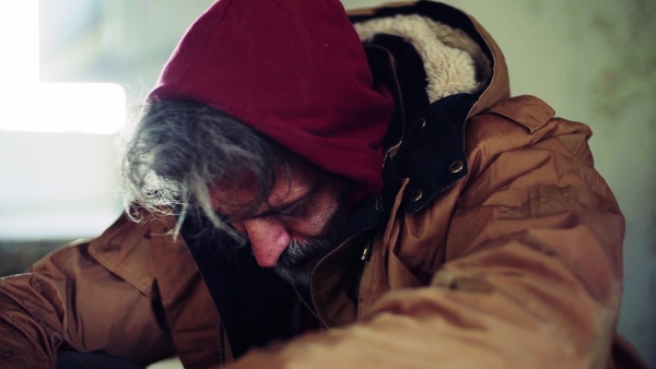 A close up portrait of homeless dirty beggar man sitting outdoors. Slow motion.