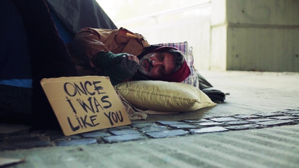 A homeless beggar man lying outdoors in a tent in city. Slow motion.