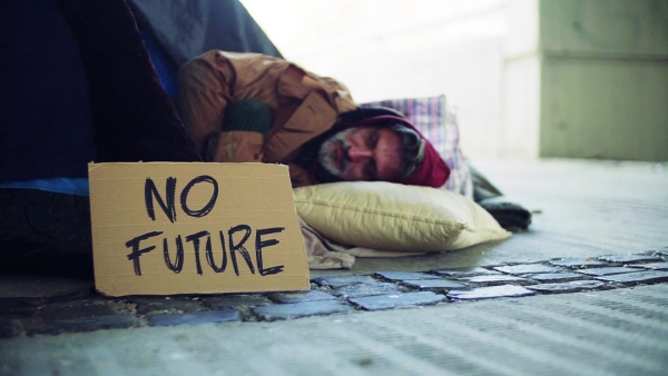 Homeless beggar man lying outdoors in city in a sleeping bag, no future cardboard sign near him. Slow motion.