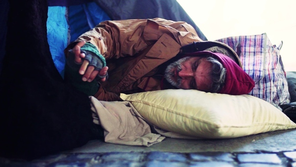 A homeless beggar man lying outdoors in a tent in city. Slow motion.