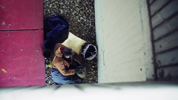 A top view of homeless beggar man lying on the ground outdoors in city asking for money donation. Slow motion.