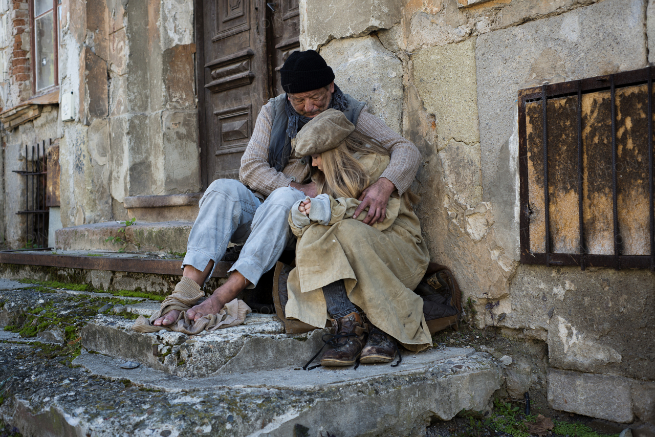 Homeless family. Homeless father with young daughter sitting on stairs