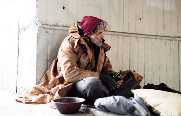 A homeless beggar man sitting outdoors in city asking for money donation.