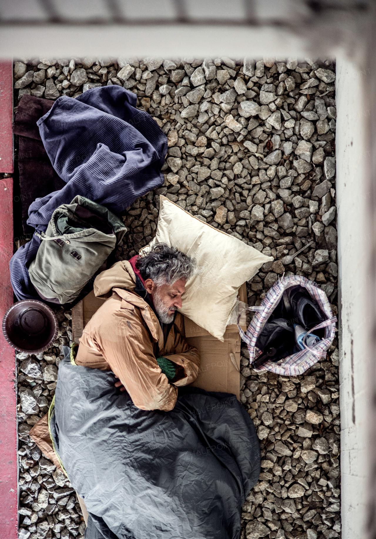 A top view of homeless beggar man lying on the ground outdoors in city asking for money donation, sleeping.