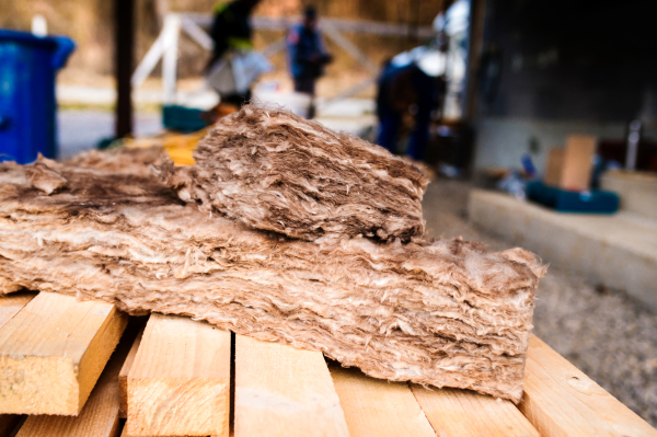 Pieces of glass insulation wool laying on wooden beams laying on construction site