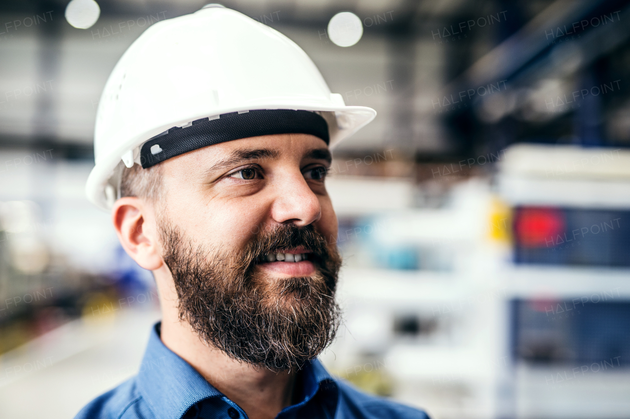 A portrait of a happy industrial man engineer with helmet in a factory.