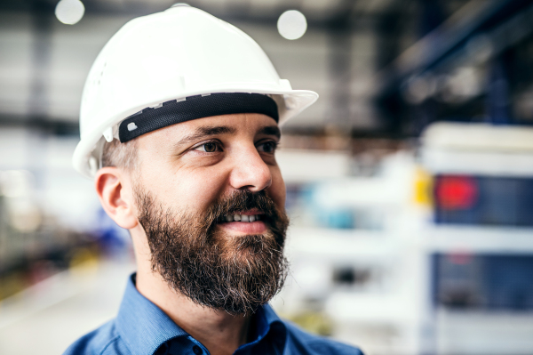 A portrait of a happy industrial man engineer with helmet in a factory.