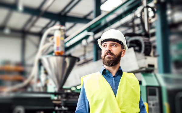 A portrait of a happy industrial man engineer standing in a factory. Copy space.