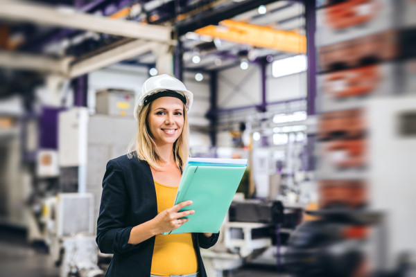 A portrait of a young industrial woman engineer in a factory, checking something.