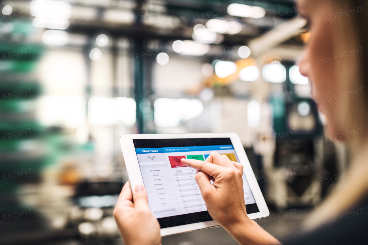 An unrecognizable industrial woman engineer in a factory using tablet.