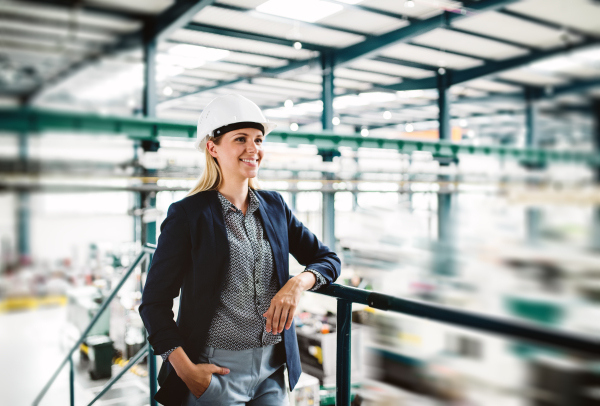 A portrait of a young industrial woman engineer standing in a factory.